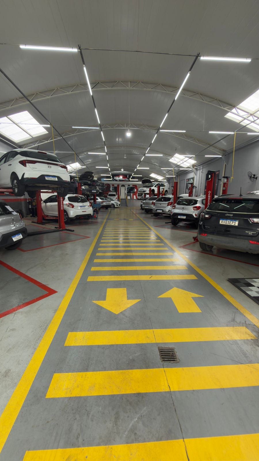 Corredor da oficina DreamCar com carros nos elevadores